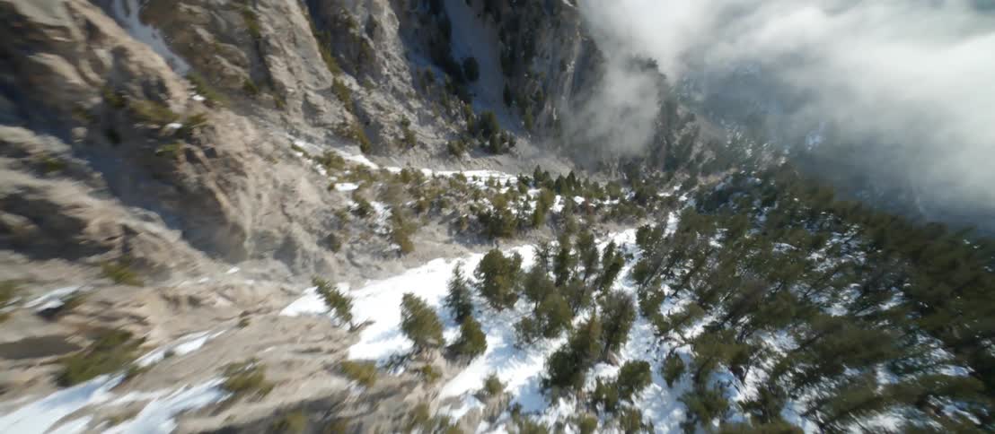 Zooming down a rocky mountain ridge with snow and trees