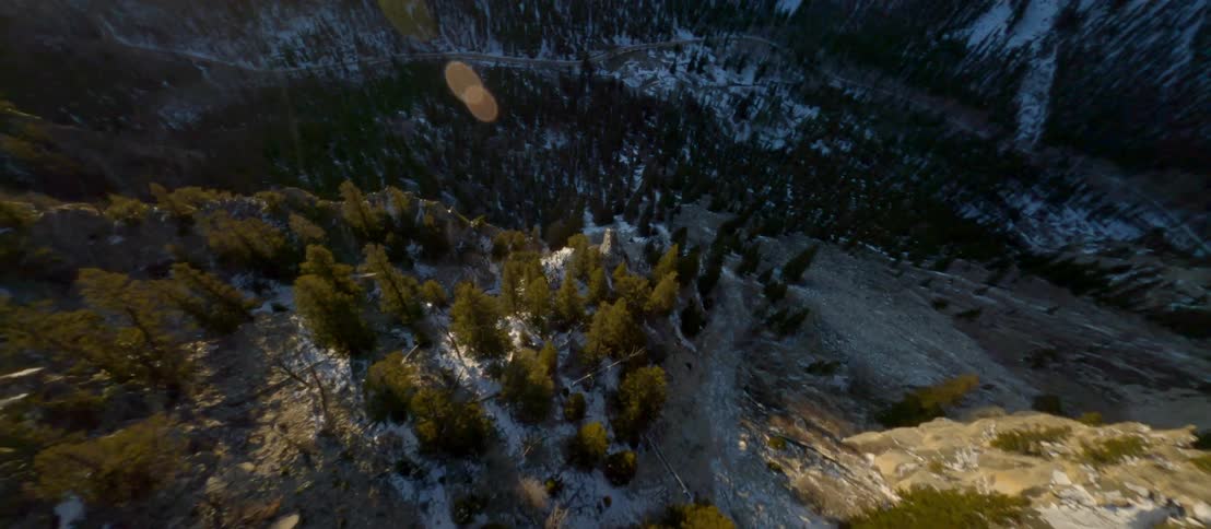 Aerial view of a steep mountain slope and a deep valley covered with snow