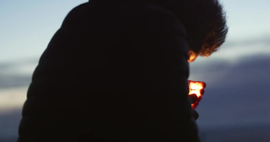 A man is trying to light a cigarette on a windy day