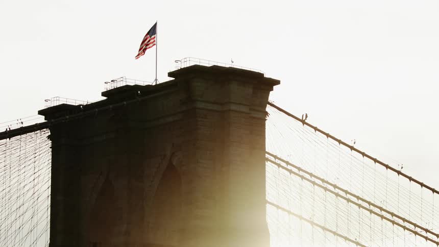The sun is rising behind the bridge