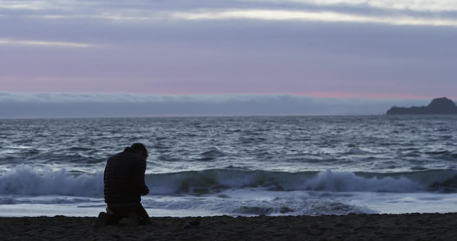 A man is sitting at a beach