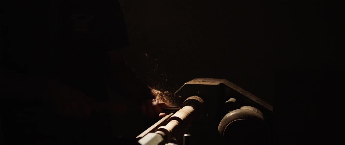 A person is carving a piece of wood on a spindle