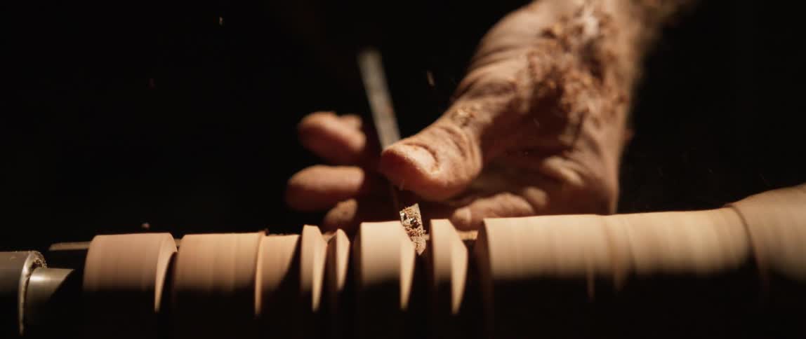 A person is carving wood on a spinner