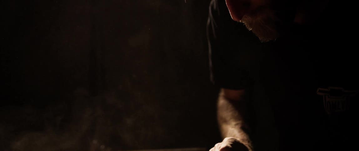 Man sands surface in a dimly lit room