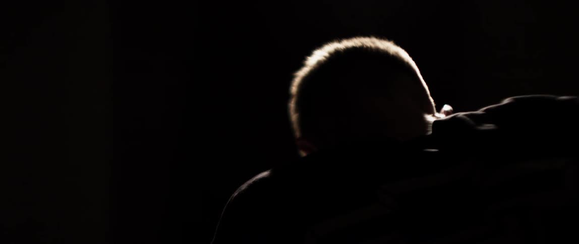 A man bends over in the darkness