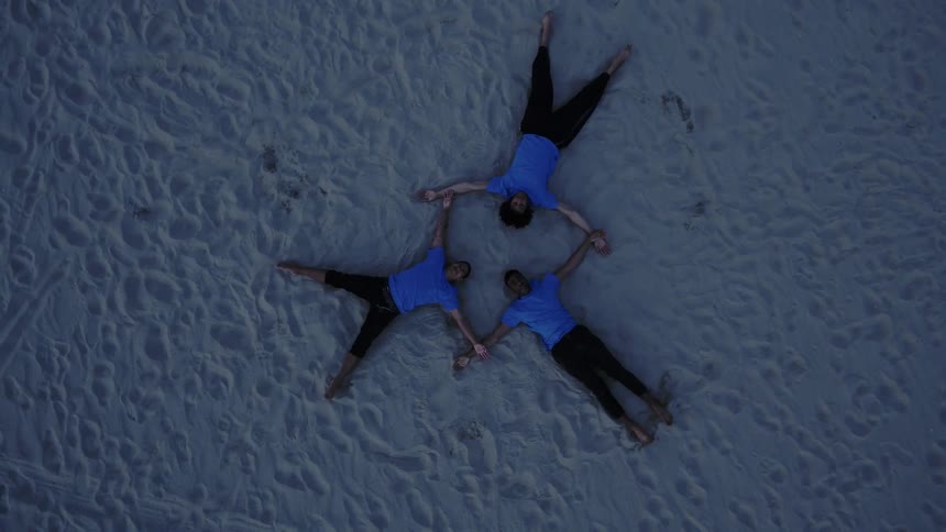 Three teenagers do sit ups in the sand