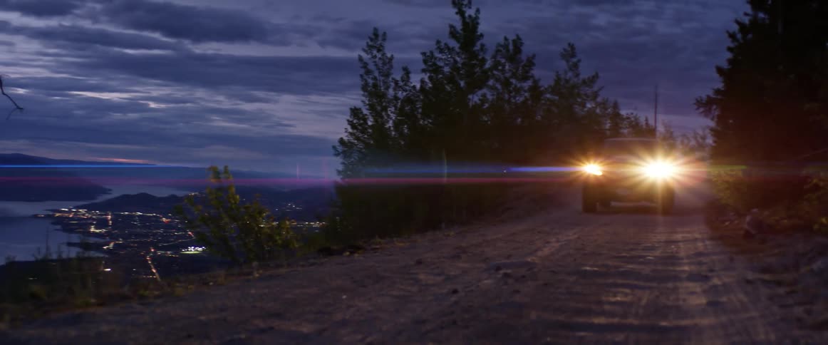 A car with bright headlights drives down a road