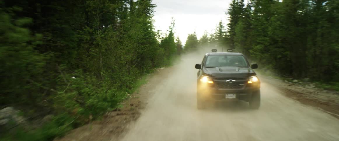 Sport utility vehicle driving along a dirt road in the woods