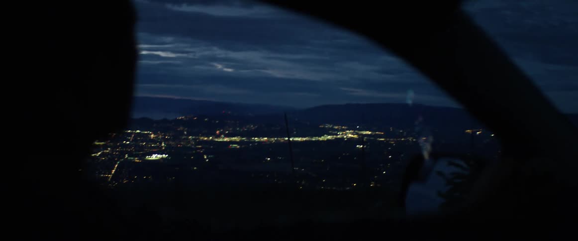 Man driving on a downhill road is silhouetted against the skyline at dusk