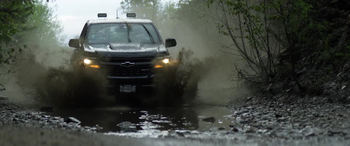 Sport utility vehicle driving through mud puddles in the backwoods