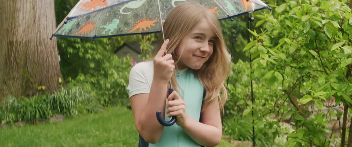 A child twists an umbrella in the yard