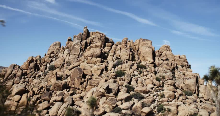 Large pile of rocks sits by the trees under a blue sky