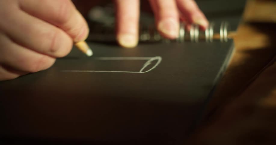 A person is drawing in a black notebook
