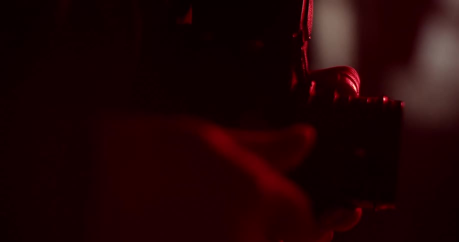 Photographer rolling film on a camera in a room with red lights