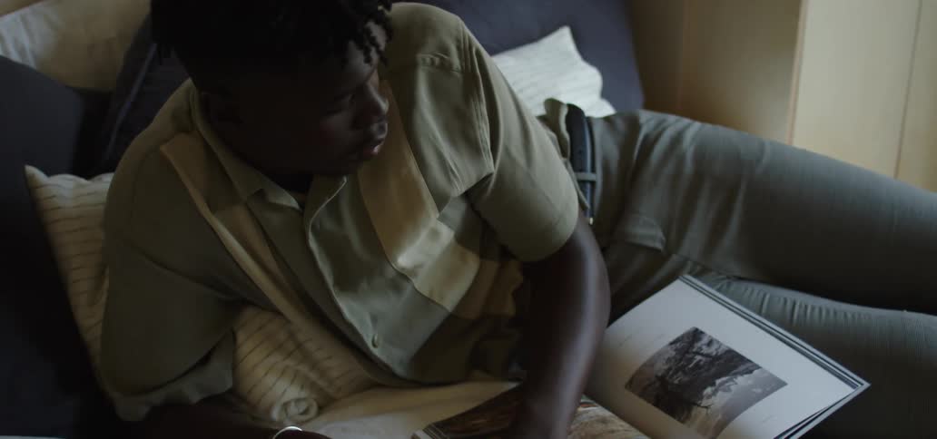 A man lays on his bed with a laptop and books studying