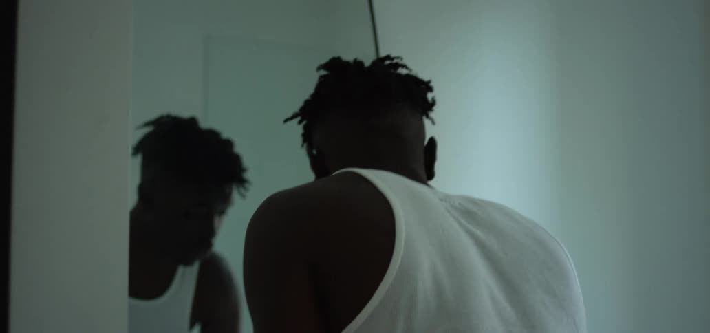 A man stands at a bathroom sink washing his hands in front of a mirror