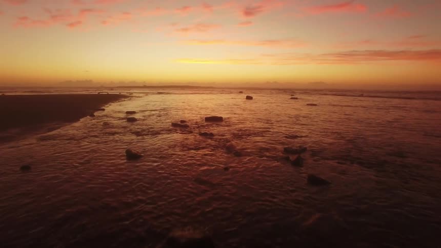 Flowing ocean waters under a yellow and orange dusk sky