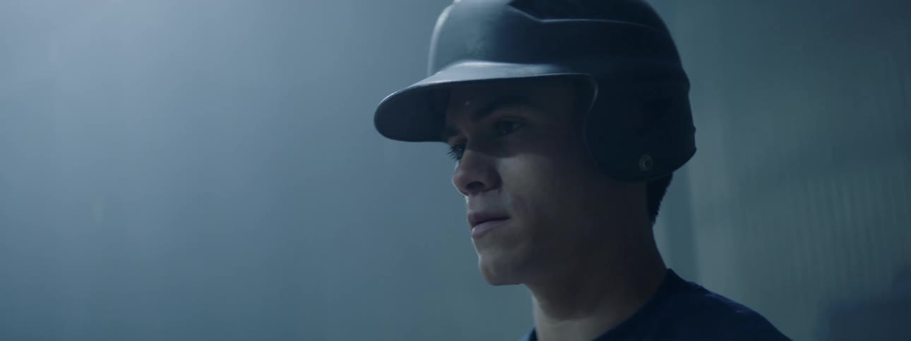 A man is putting on a baseball helmet