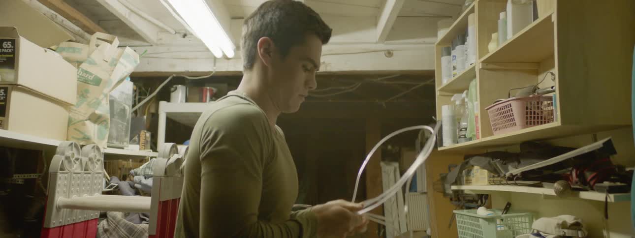 A white man ties up a piece of cable in a cramped room