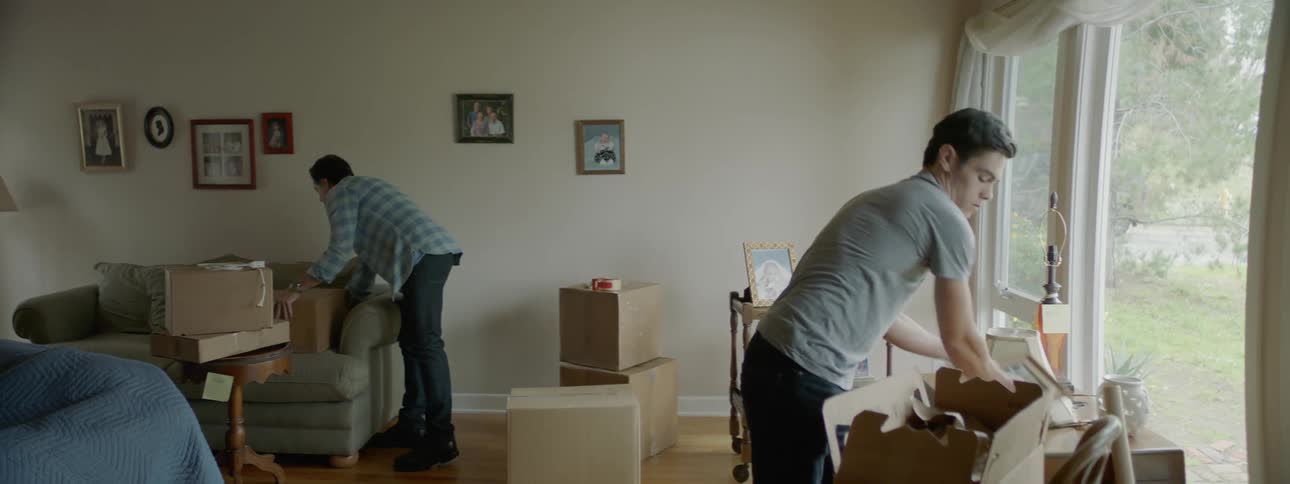 Two men are packing boxes in a house