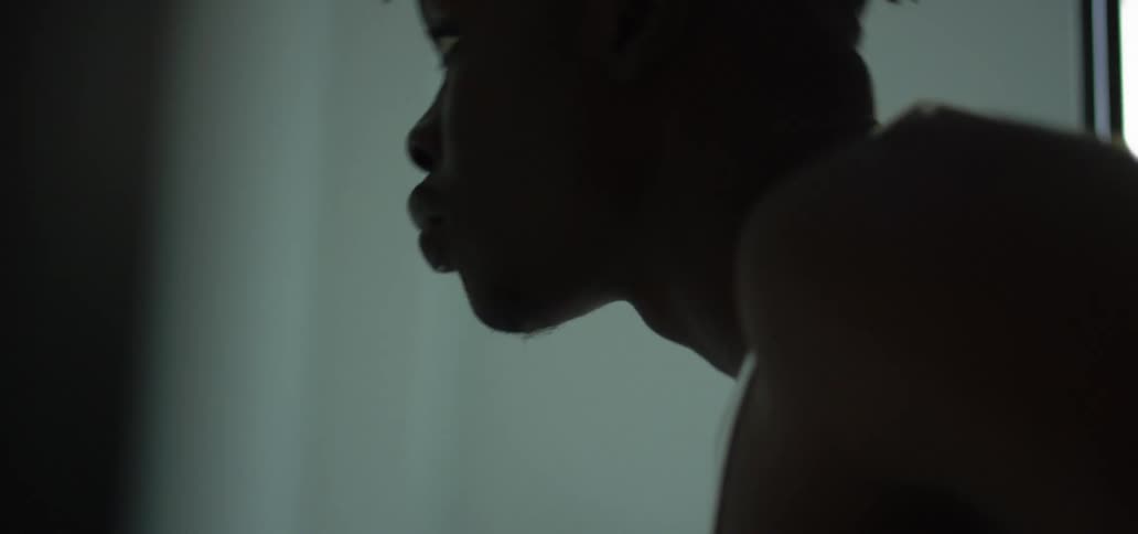 Black man with a white undershirt looks in a mirror