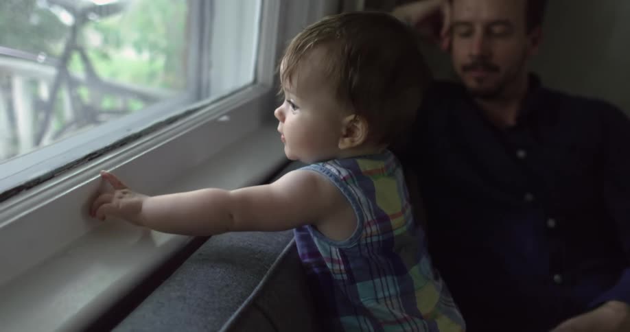 Father touches child as child looks out window a bicycle can be seen through
