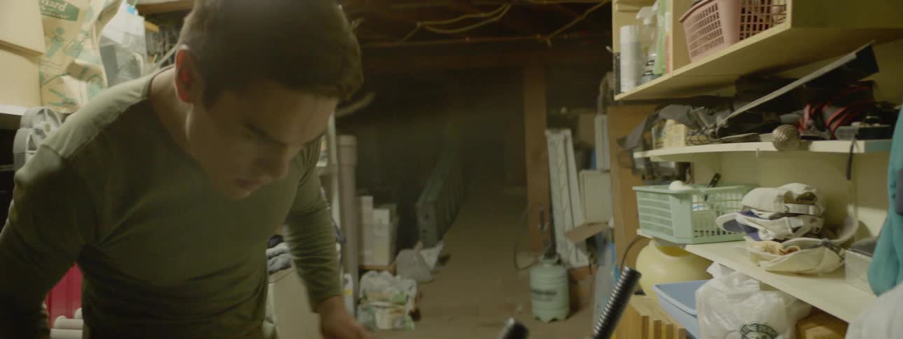 Young man searches for string or cord in a basement