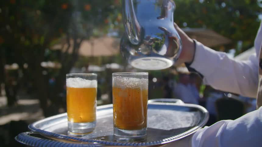 Server pouring a drink from metal pitcher outdoors