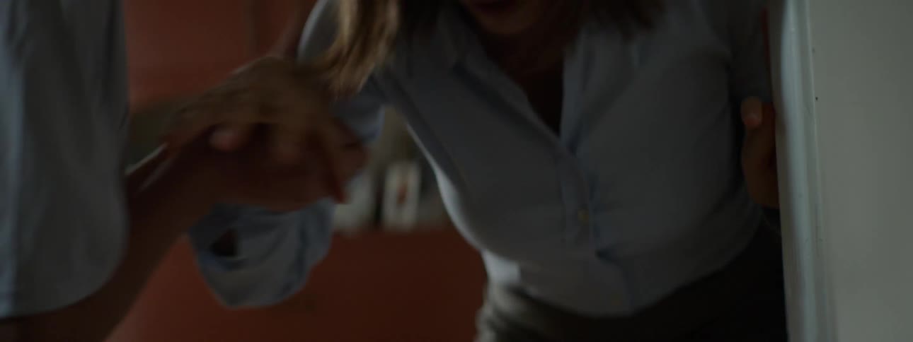 A distressed woman tries to walk through a hall but begins to cough and falls to her knees as young man comes to check on her