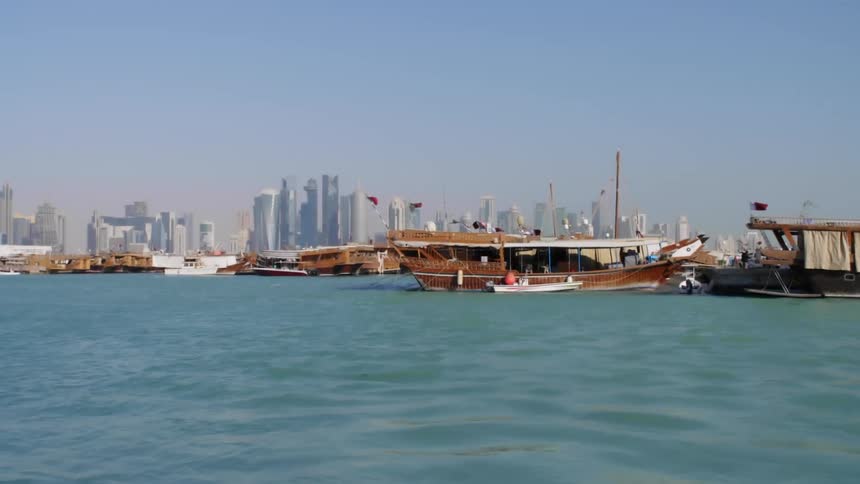 Boats parked at a harbor with the city skyline in the distance