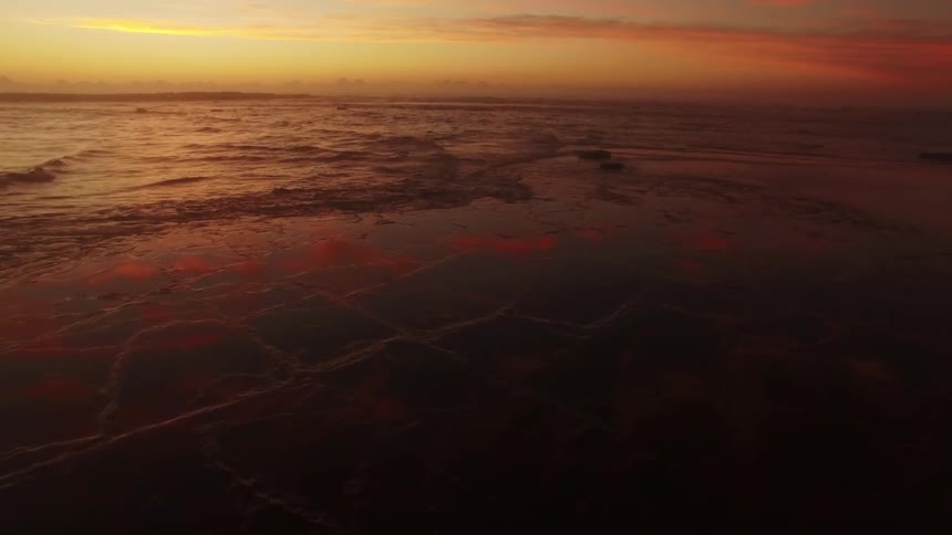 Waves lapping against the beach as the sun sets