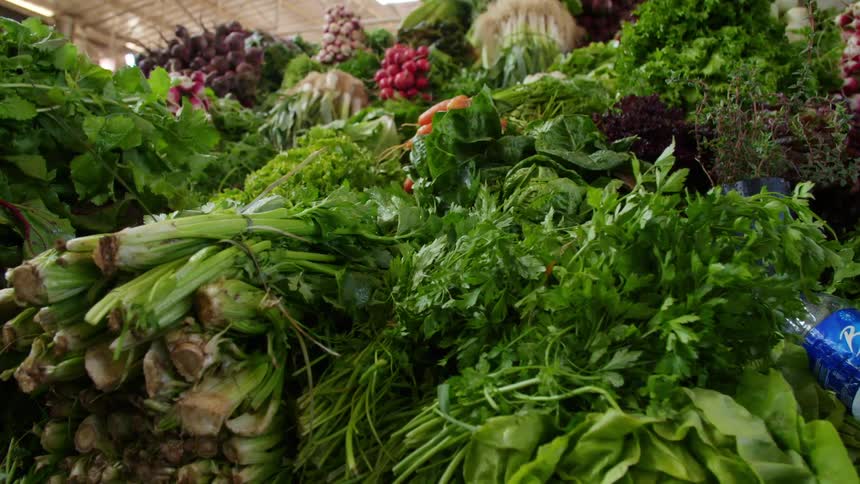 Bunches of vegetables and herbs on display at a market