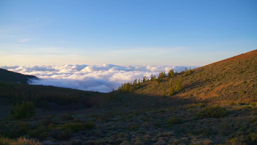 The clouds roll over the green on a mountain