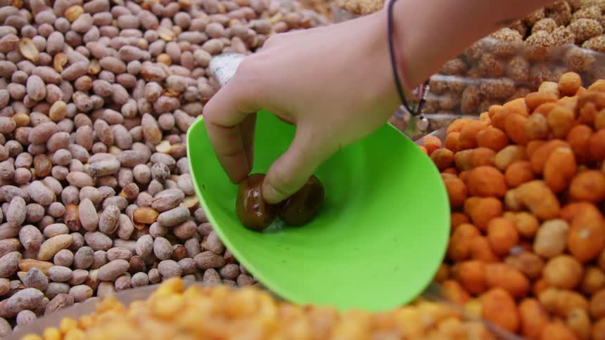 A woman picks a date up from a scoop in a bulk section in a store