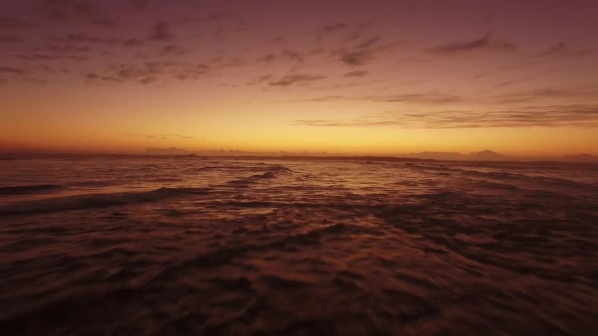 Ocean waves wash ashore at sunset