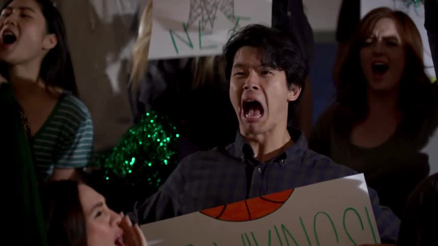 A group of people are cheering at a basketball game