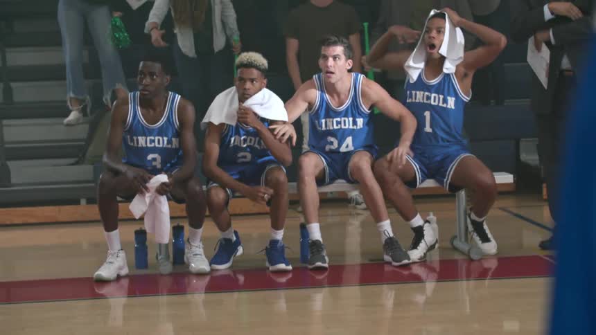 Basketball players watch teammate make penalty shot and cheer