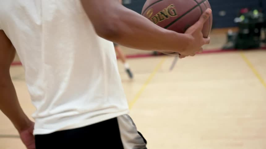 A group of athletes are playing basketball indoors