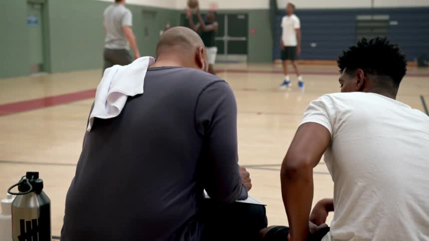 Basketball player sitting in bench with coach