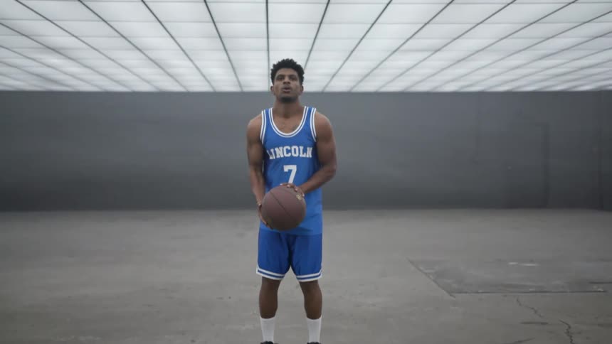 A basketball player bounces the ball and takes a deep breath as he prepares to shoot