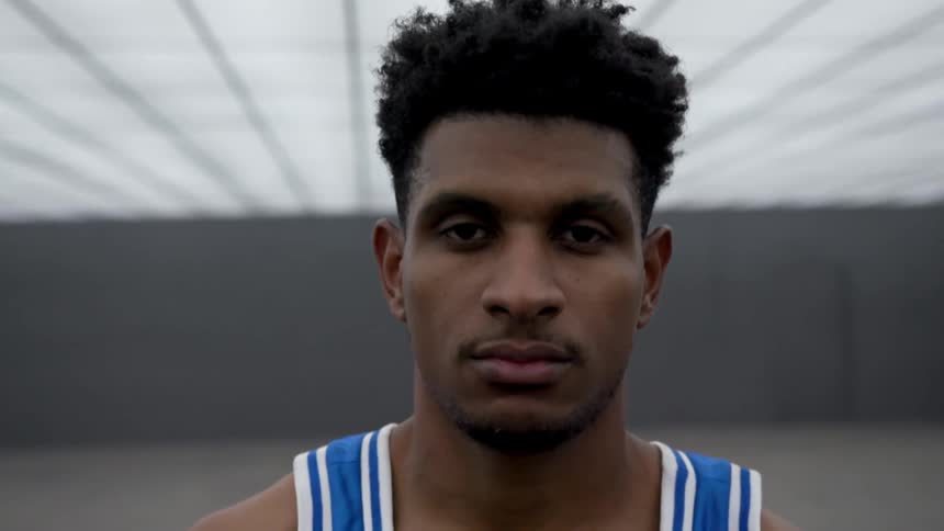 A basketball player dribbles In a futuristic room
