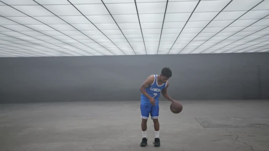 A man standing in a room dribbling a basketball