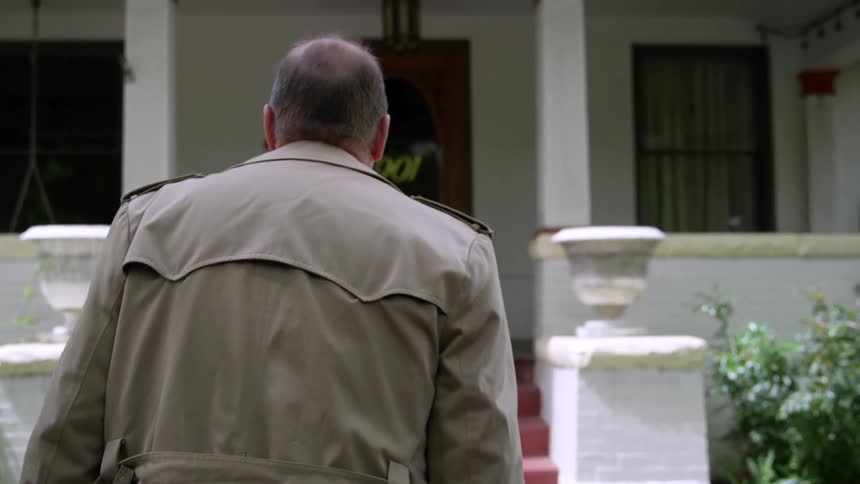 Man wearing a coat approaches the door of a house