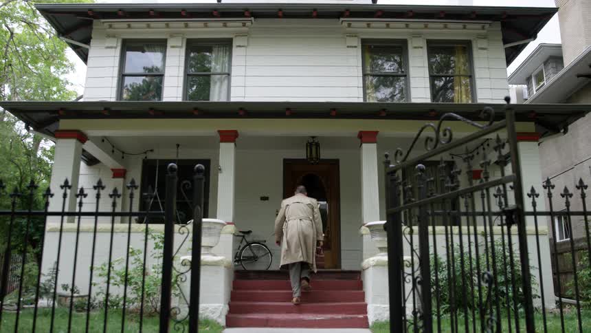 A man walks up the front stairs to his home