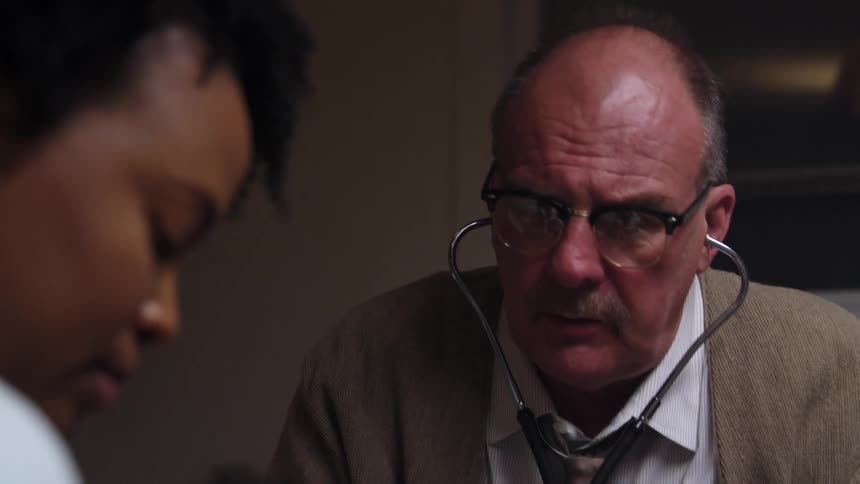 A male doctor puts a stethoscope to his ears and listens to an infant patient in front of him