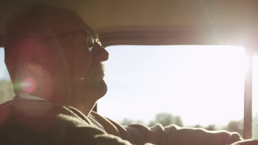 Elderly man driving a car at sunset