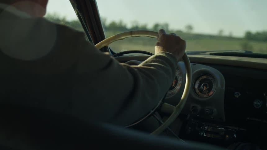 An elderly man drives a car