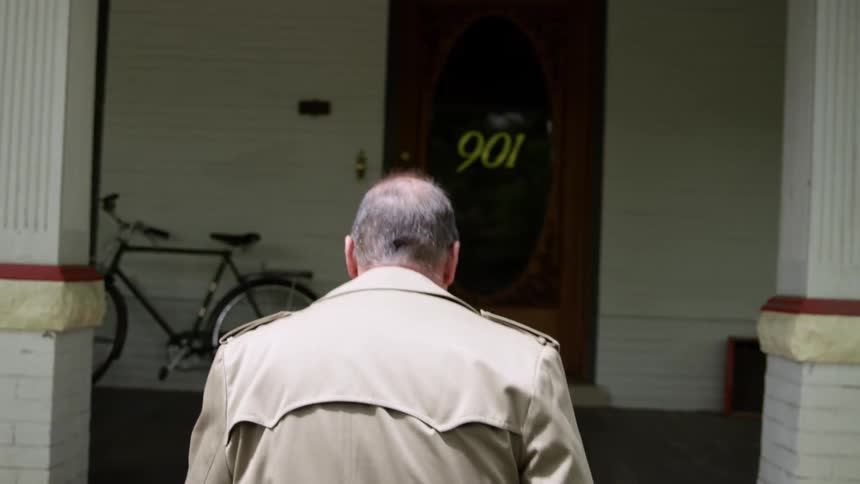 A man walks up the front steps to his home