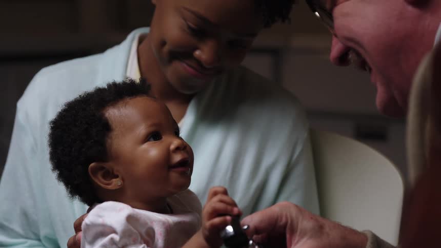 A woman holds her baby daughter as a doctor examines her