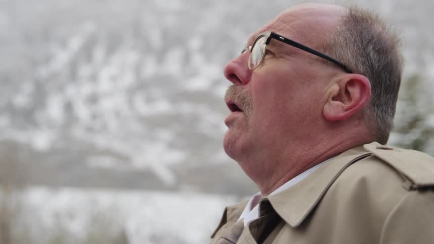 A man stands outside as it snows
